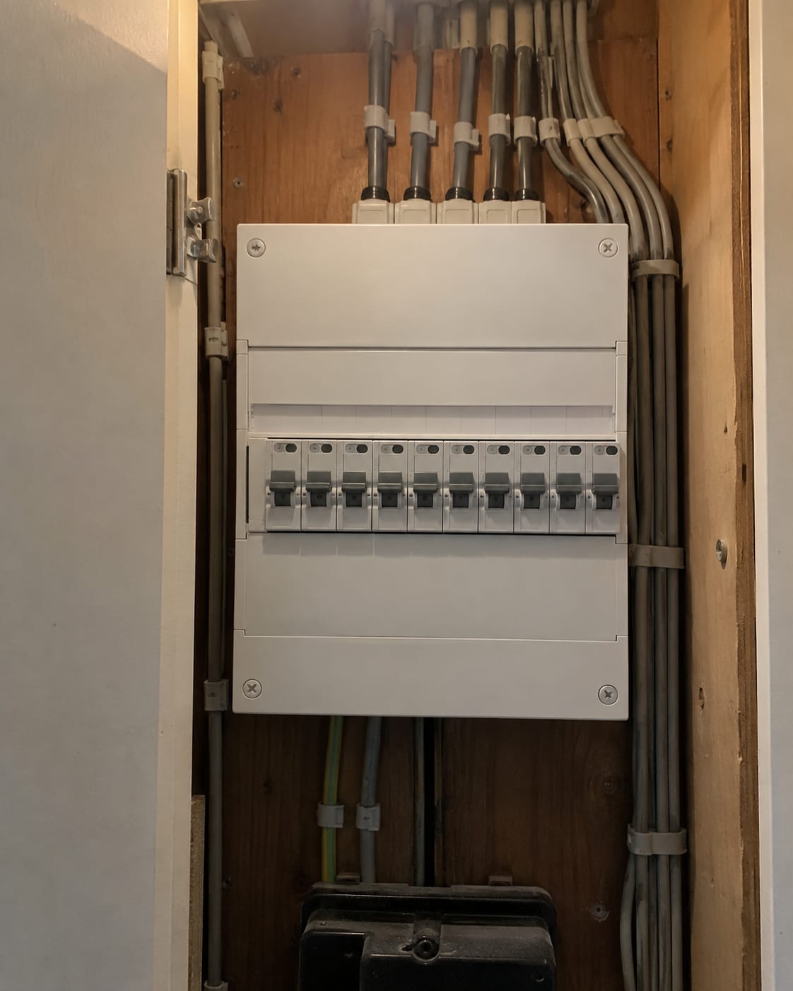 In de meterkast hangt een nieuwe groepenkast met een rij aardlekautomaten achter een witte afdekplaat.