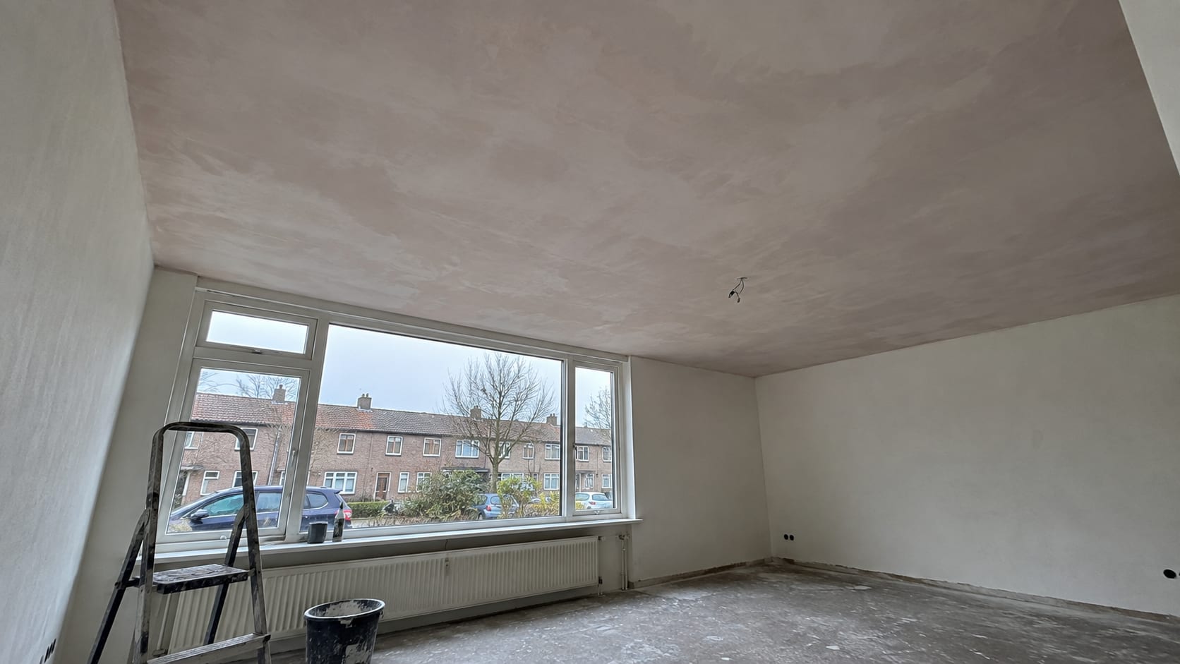 Woonkamer met een strak gestuukt plafond, klaar om gesaust te worden
